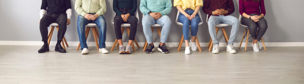 Cropped image of unrecognizable people sitting in the waiting room on chairs in line for interview